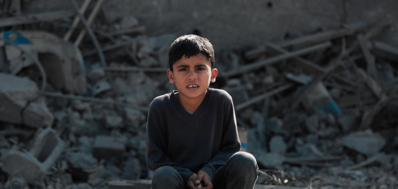 Ein Kind sitzt zwischen Trümmern